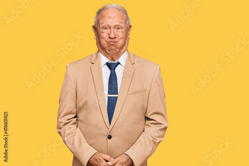 Fotografija Senior caucasian man wearing business suit and tie puffing cheeks with funny face