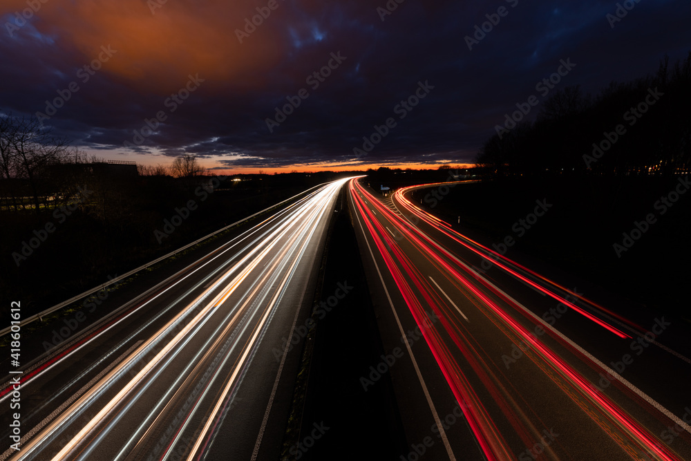 Autobahn bei Nacht mit fahrenden Autos. Langzeitbelichtung mit dramatischen Himmel 