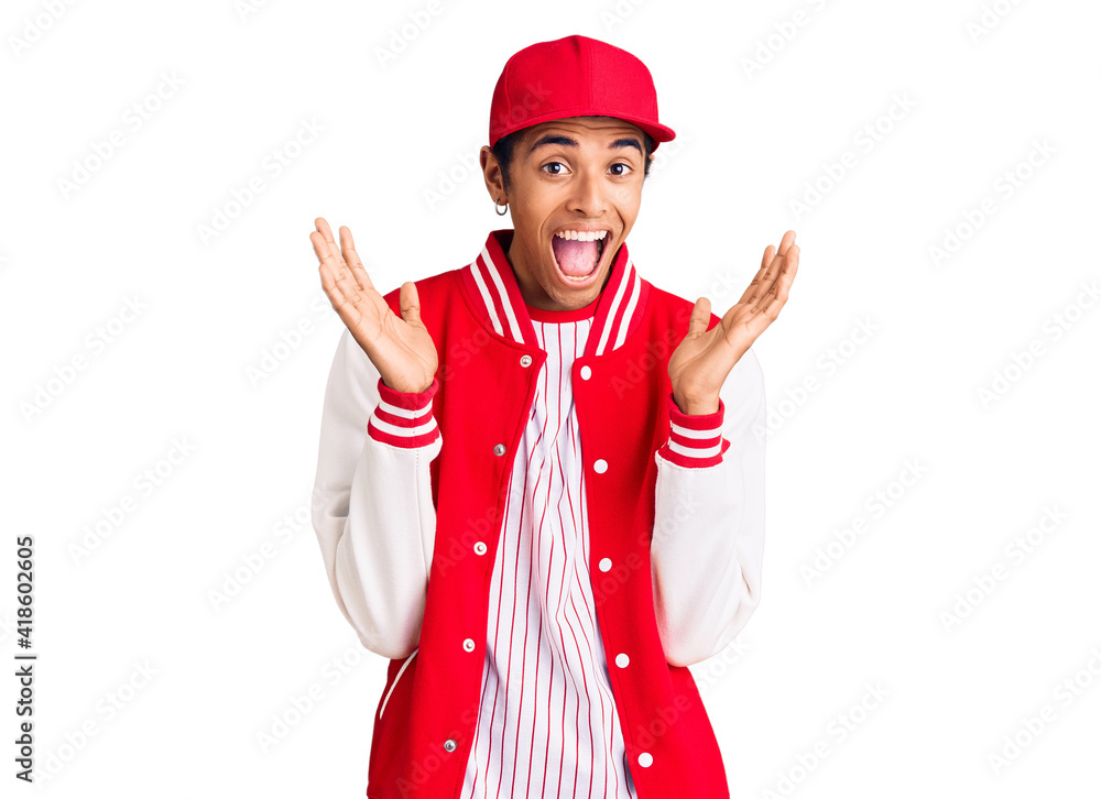 Young african amercian man wearing baseball uniform celebrating crazy and amazed for success with arms raised and open eyes screaming excited. winner concept Young african amercian man wearing baseball uniform celebrating crazy and amazed for success with arms raised and open eyes screaming excited. winner concept