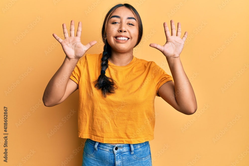 Young latin woman wearing casual clothes showing and pointing up with fingers number ten while smiling confident and happy. Young latin woman wearing casual clothes showing and pointing up with fingers number ten while smiling confident and happy.