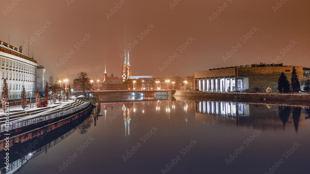 The University Library in Wroclaw on the banks of the Odra River, illuminated at night.