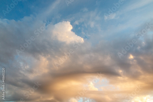 Fototapeta Naklejka Na Ścianę i Meble -  White and orange cotton-textured clouds spread across a blue sky to the horizon