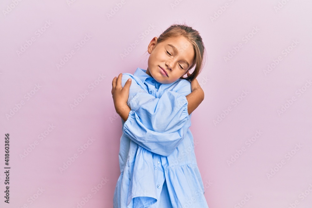 Little beautiful girl wearing casual clothes hugging oneself happy and positive, smiling confident. self love and self care Little beautiful girl wearing casual clothes hugging oneself happy and positive, smiling confident. self love and self care