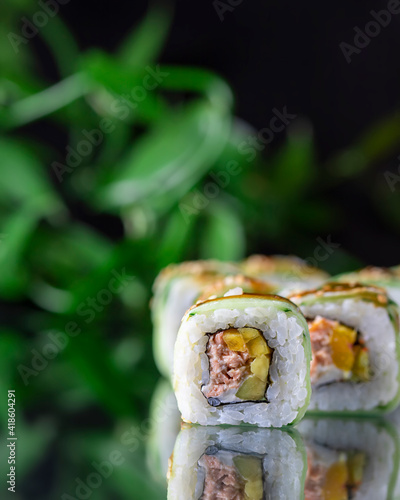 Macro view of Japanese Cuisine Sushi Roll on mirror black background.