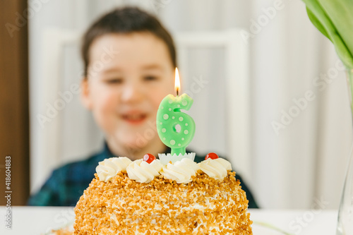 Child celebrates his 6th birthday. Happy children s birthday. . Burning candle in the form of the number 6. Cake with candle 