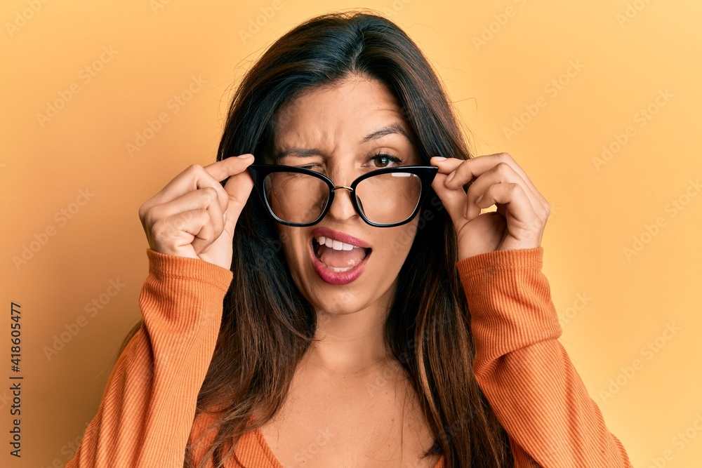Beautiful hispanic woman wearing glasses winking looking at the camera with sexy expression, cheerful and happy face. Beautiful hispanic woman wearing glasses winking looking at the camera with sexy expression, cheerful and happy face.