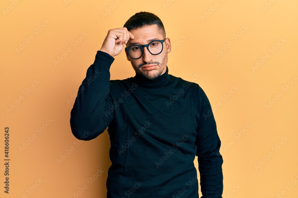 Handsome man with tattoos wearing turtleneck sweater and glasses worried and stressed about a problem with hand on forehead, nervous and anxious for crisis Handsome man with tattoos wearing turtleneck sweater and glasses worried and stressed about a problem with hand on forehead, nervous and anxious for crisis