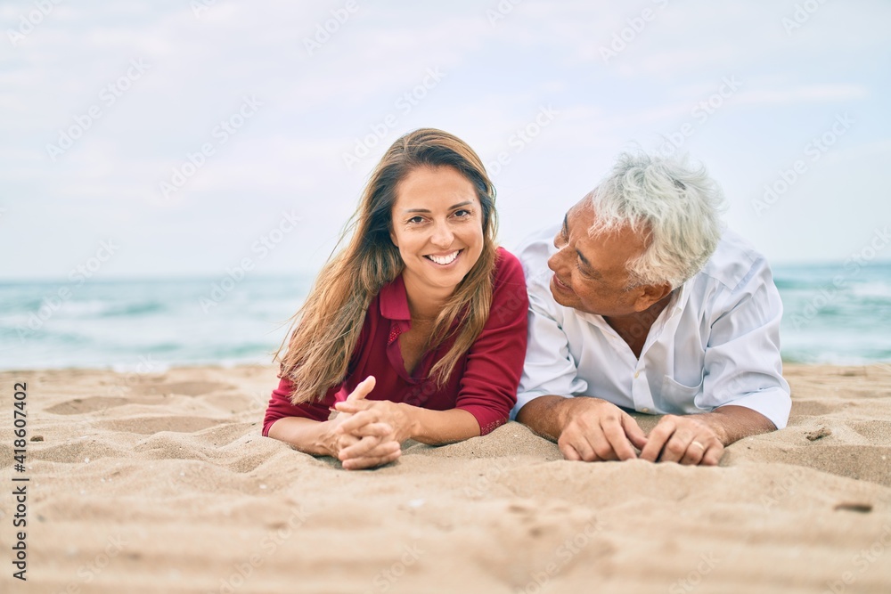 Middle age couple in love lying on the sand at the beach happy and cheerful together Middle age couple in love lying on the sand at the beach happy and cheerful together