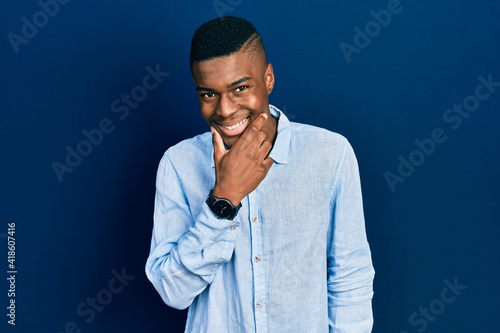 Young african american man wearing casual clothes looking confident at the camera smiling with crossed arms and hand raised on chin. thinking positive. © Krakenimages.com