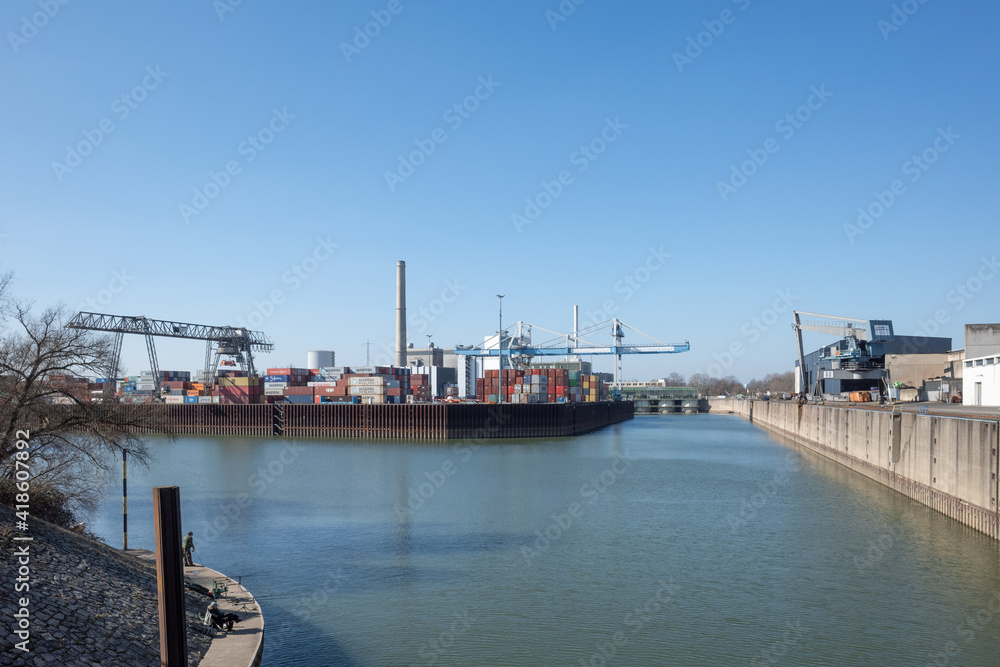 Outdoor sunny view at Düsseldorf-Hafen with Shipyard cranes or portal cranes, harbour port and stack of containers against blue sky.