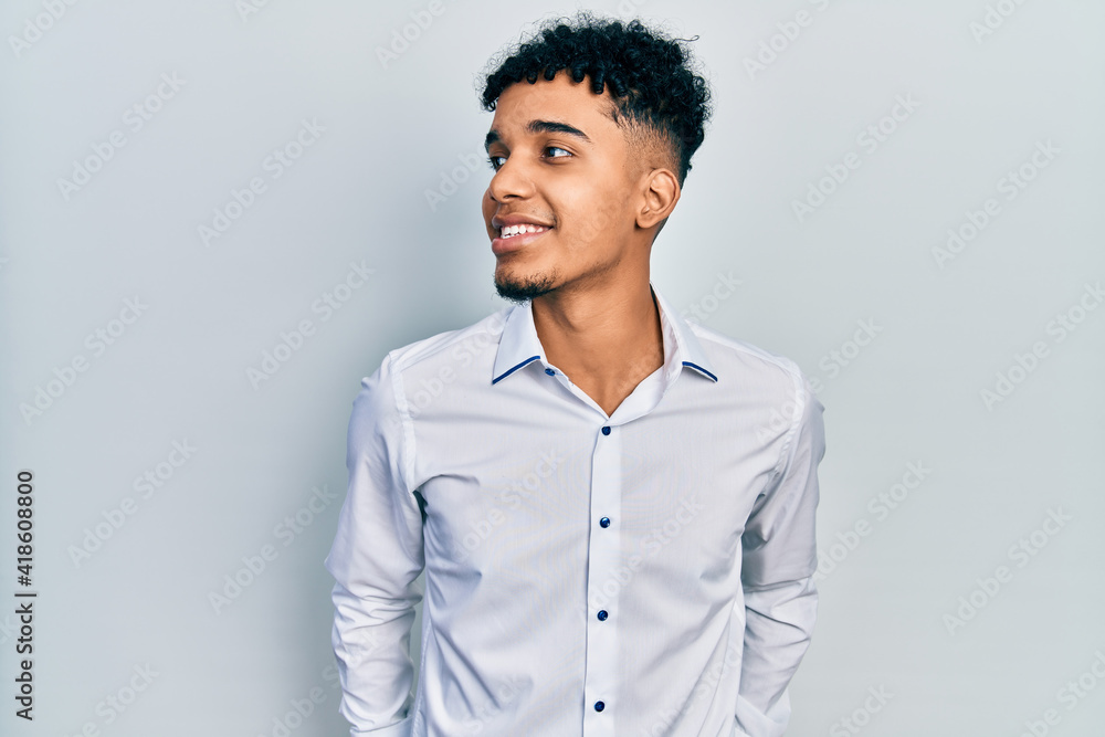 Young african american man wearing business shirt looking to side, relax profile pose with natural face and confident smile. Young african american man wearing business shirt looking to side, relax profile pose with natural face and confident smile.