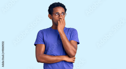 African handsome man wearing casual clothes and glasses looking stressed and nervous with hands on mouth biting nails. anxiety problem. © Krakenimages.com