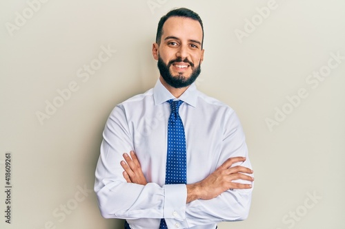 Young man with beard wearing business tie happy face smiling with crossed arms looking at the camera. positive person.