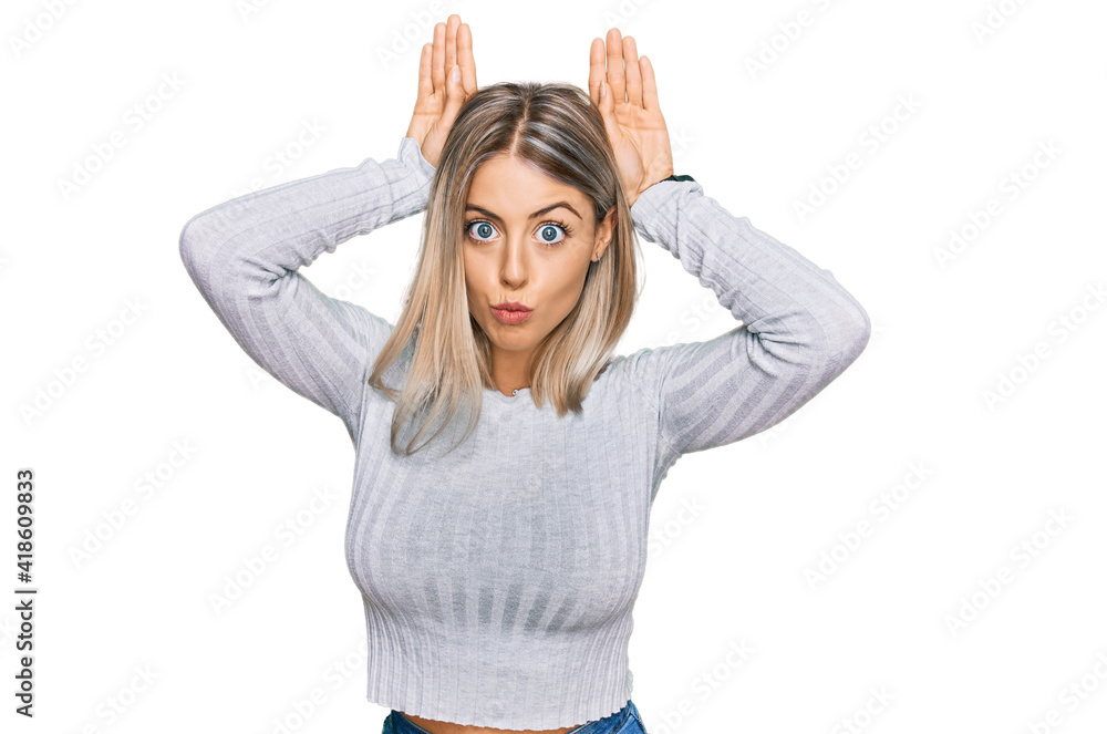 Beautiful blonde woman wearing casual clothes doing bunny ears gesture with hands palms looking cynical and skeptical. easter rabbit concept.