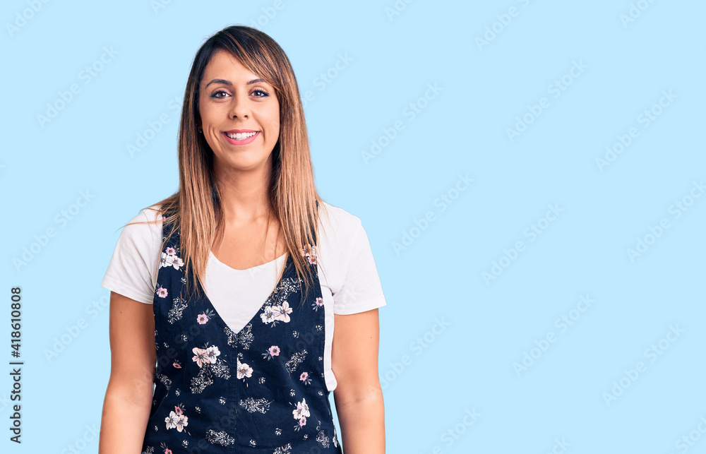 Young beautiful woman wearing casual floral dress looking positive and happy standing and smiling with a confident smile showing teeth Young beautiful woman wearing casual floral dress looking positive and happy standing and smiling with a confident smile showing teeth