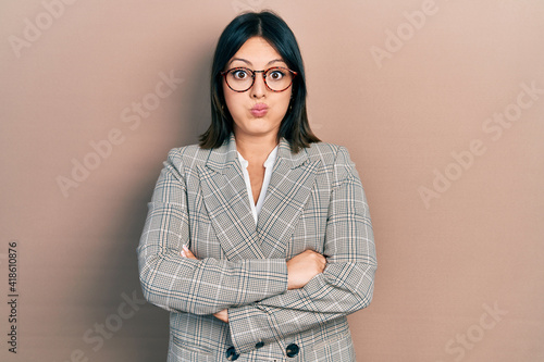 Young hispanic woman with arms crossed gesture puffing cheeks with funny face. mouth inflated with air, catching air.