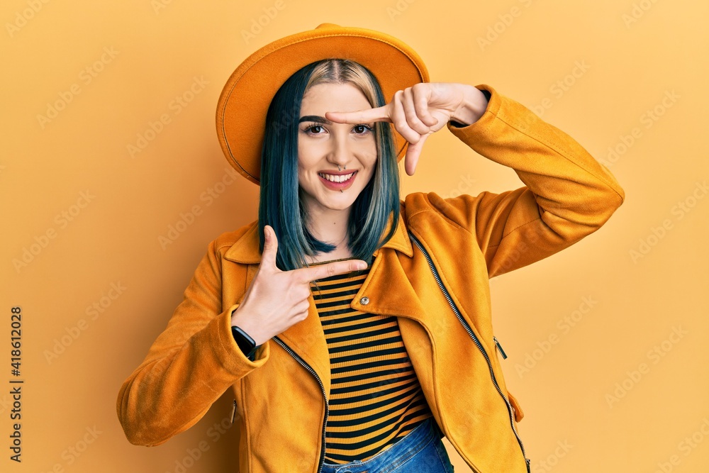 Young modern girl wearing yellow hat and leather jacket smiling making frame with hands and fingers with happy face. creativity and photography concept. Young modern girl wearing yellow hat and leather jacket smiling making frame with hands and fingers with happy face. creativity and photography concept.