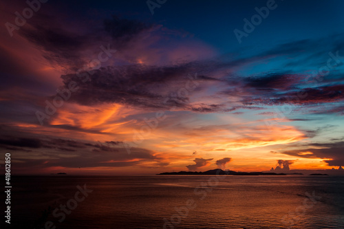 Bright sunset on sea. Orange sky, clouds over island. Thailand. 