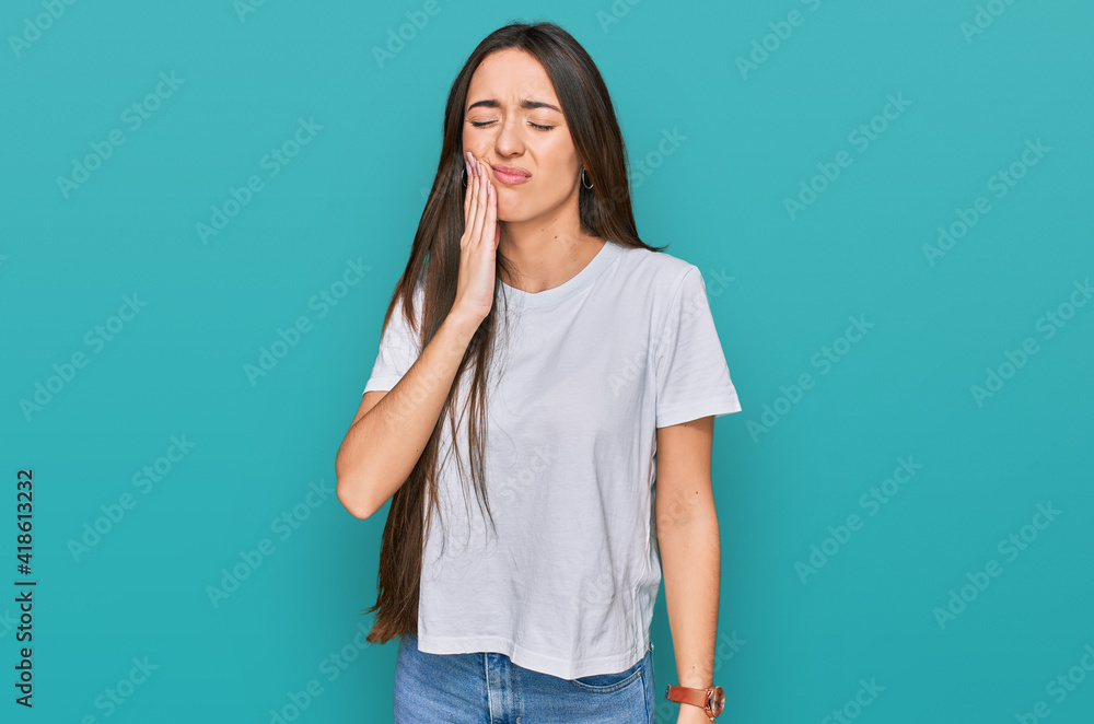 Young hispanic girl wearing casual white t shirt touching mouth with hand with painful expression because of toothache or dental illness on teeth. dentist Young hispanic girl wearing casual white t shirt touching mouth with hand with painful expression because of toothache or dental illness on teeth. dentist