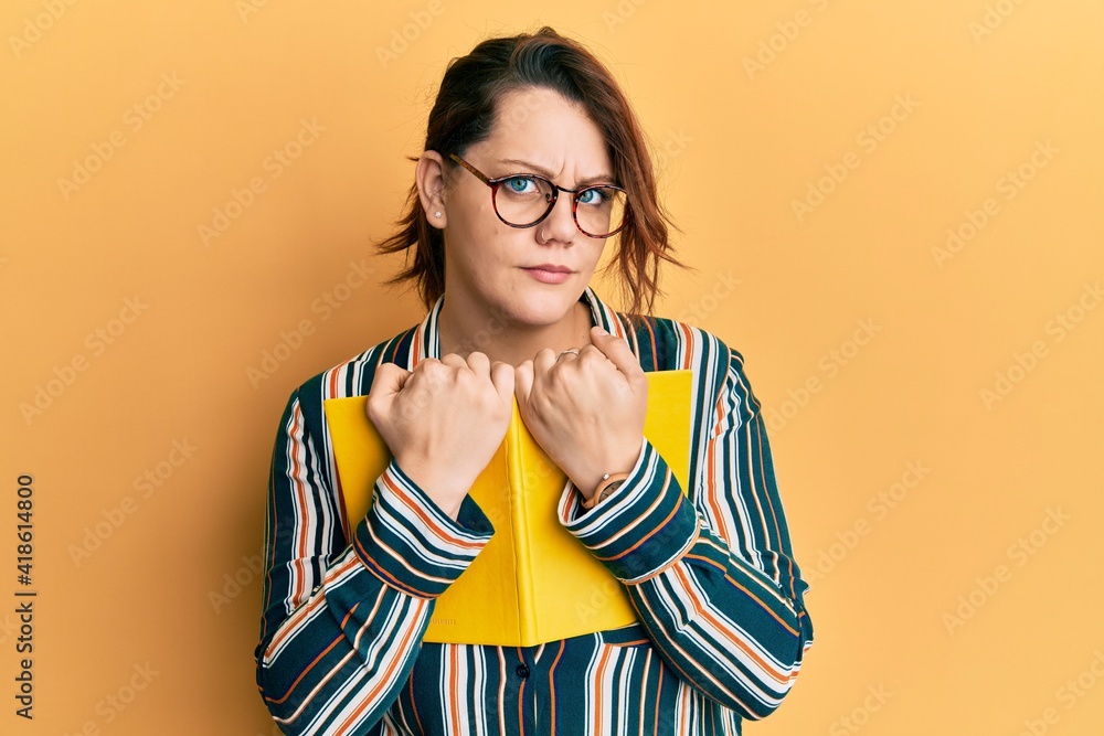 Young caucasian woman holding book skeptic and nervous, frowning upset because of problem. negative person. Young caucasian woman holding book skeptic and nervous, frowning upset because of problem. negative person.