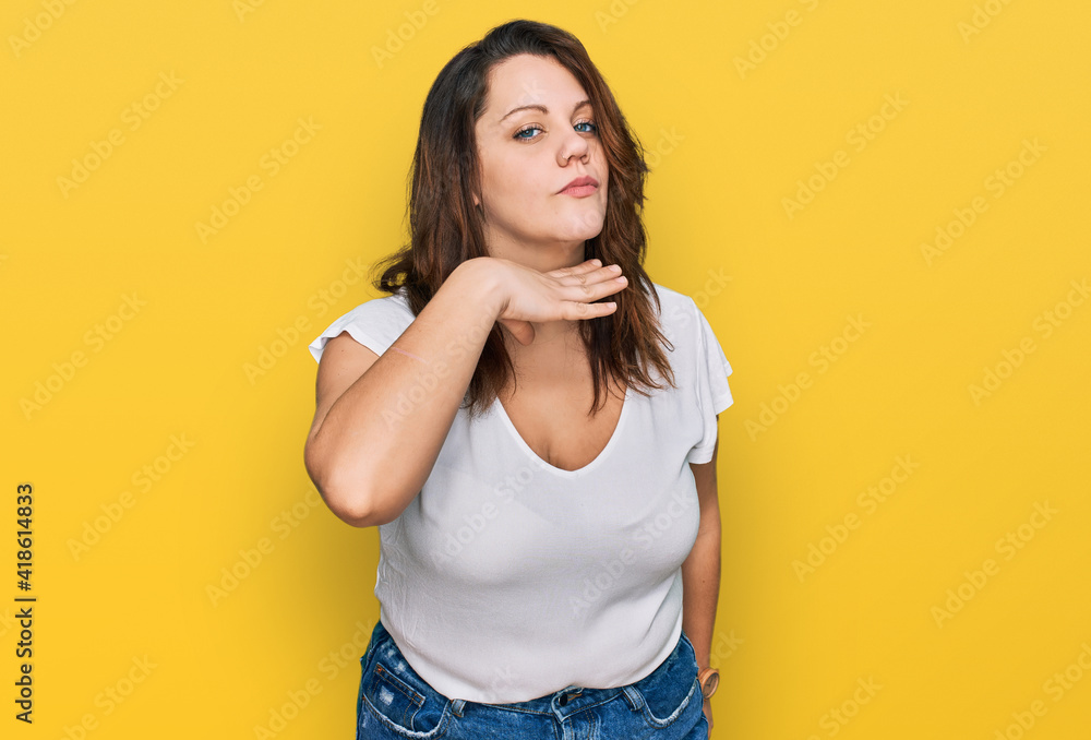 Young plus size woman wearing casual white t shirt cutting throat with hand as knife, threaten aggression with furious violence Young plus size woman wearing casual white t shirt cutting throat with hand as knife, threaten aggression with furious violence