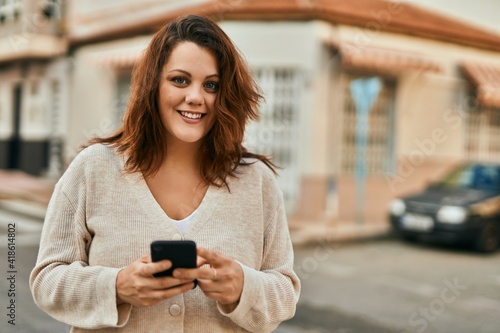 Young irish plus size girl smiling happy using smartphone at the city.