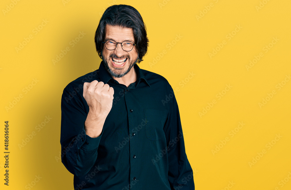 Middle age caucasian man wearing casual clothes and glasses angry and mad raising fist frustrated and furious while shouting with anger. rage and aggressive concept. Middle age caucasian man wearing casual clothes and glasses angry and mad raising fist frustrated and furious while shouting with anger. rage and aggressive concept.