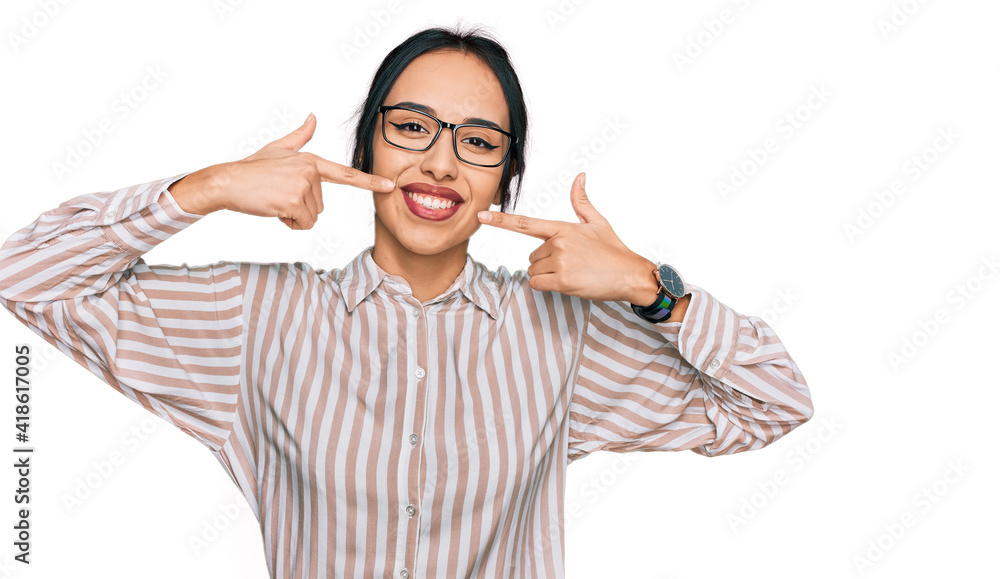Young hispanic girl wearing casual clothes and glasses smiling cheerful showing and pointing with fingers teeth and mouth. dental health concept. Young hispanic girl wearing casual clothes and glasses smiling cheerful showing and pointing with fingers teeth and mouth. dental health concept.
