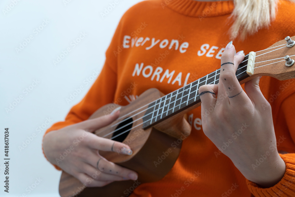 Fototapeta premium close-up. Girl's hands play ukulele ukulele on light background.