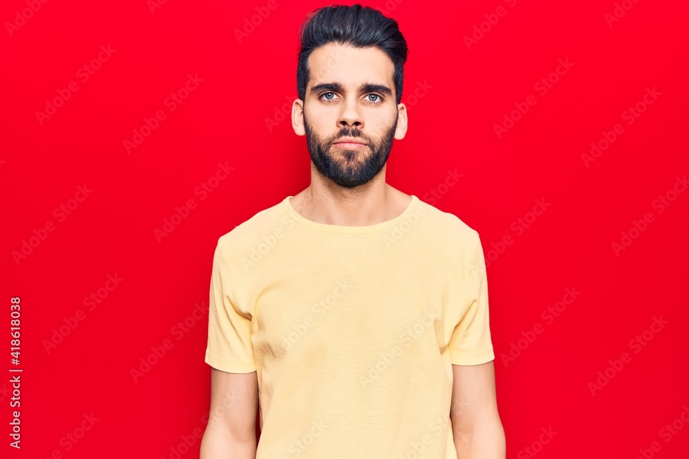 Fototapeta premium Young handsome man with beard wearing casual t-shirt with serious expression on face. simple and natural looking at the camera.