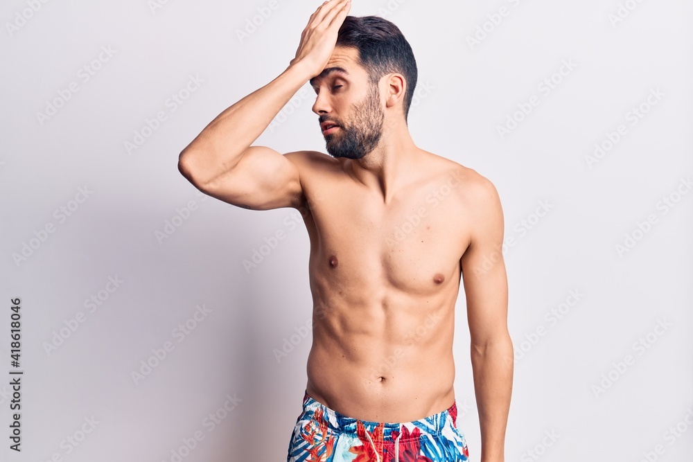 Fototapeta premium Young handsome man with beard shirtless wearing swimwear surprised with hand on head for mistake, remember error. forgot, bad memory concept.