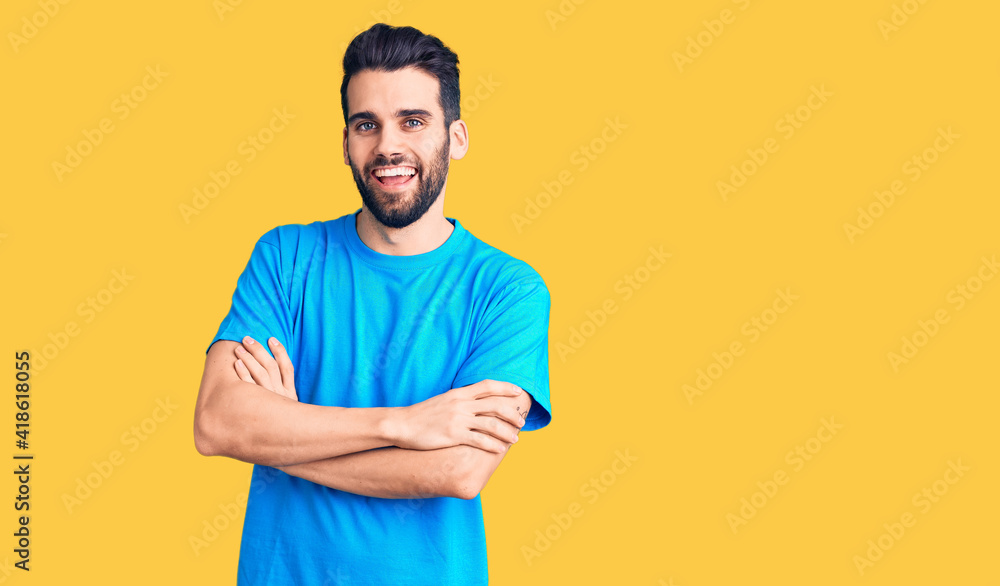 Young handsome man with beard wearing casual t-shirt happy face smiling with crossed arms looking at the camera. positive person. Young handsome man with beard wearing casual t-shirt happy face smiling with crossed arms looking at the camera. positive person.