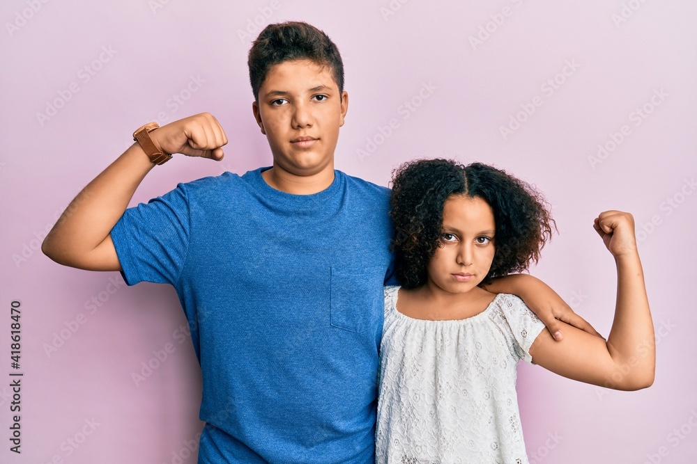 Obraz premium Young hispanic family of brother and sister wearing casual clothes together strong person showing arm muscle, confident and proud of power