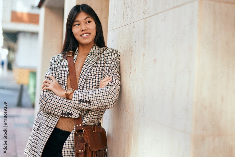 Young asian businesswoman with arms crossed smiling happy at the city.