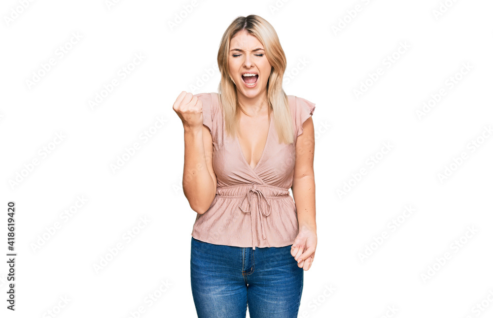 Young caucasian woman wearing casual clothes angry and mad raising fist frustrated and furious while shouting with anger. rage and aggressive concept. Young caucasian woman wearing casual clothes angry and mad raising fist frustrated and furious while shouting with anger. rage and aggressive concept.