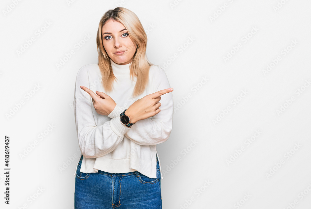 Young caucasian woman wearing casual winter sweater pointing to both sides with fingers, different direction disagree Young caucasian woman wearing casual winter sweater pointing to both sides with fingers, different direction disagree