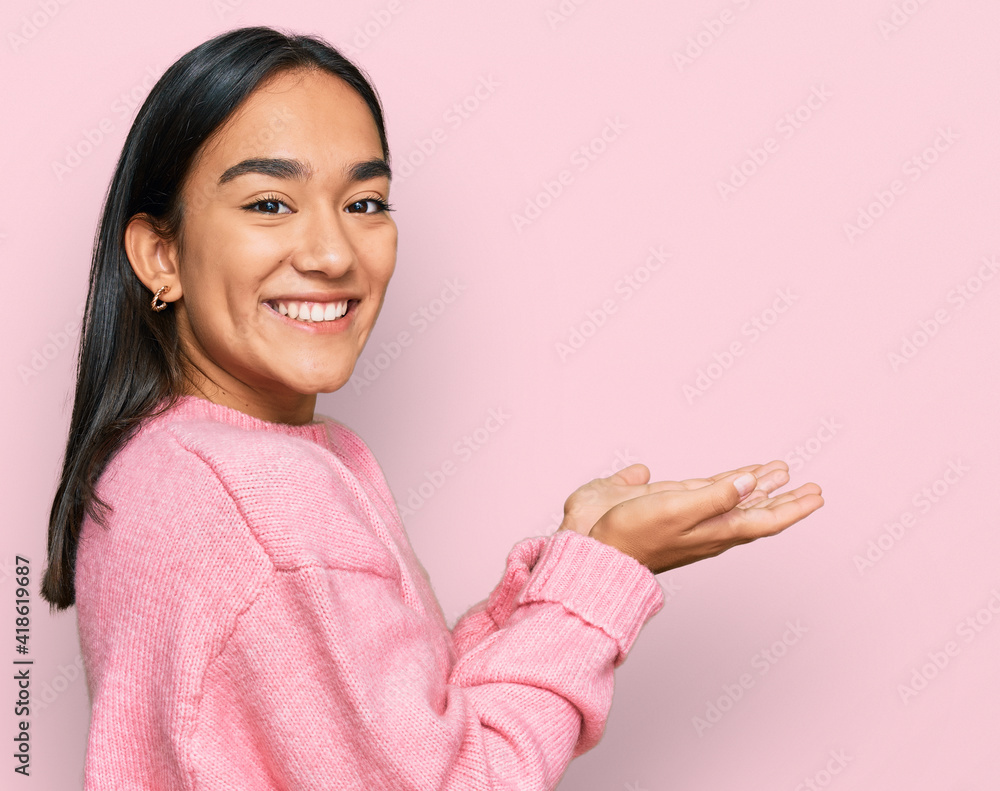 Young asian woman wearing casual winter sweater pointing aside with hands open palms showing copy space, presenting advertisement smiling excited happy Young asian woman wearing casual winter sweater pointing aside with hands open palms showing copy space, presenting advertisement smiling excited happy