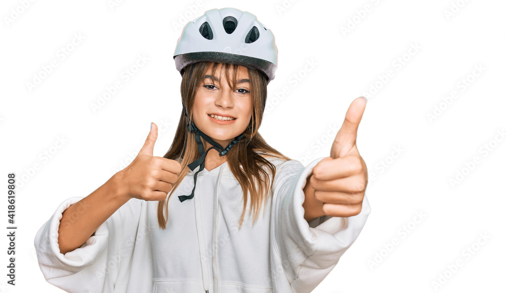 Teenager caucasian girl wearing bike helmet approving doing positive gesture with hand, thumbs up smiling and happy for success. winner gesture. Teenager caucasian girl wearing bike helmet approving doing positive gesture with hand, thumbs up smiling and happy for success. winner gesture.