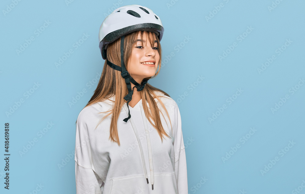 Teenager caucasian girl wearing bike helmet looking away to side with smile on face, natural expression. laughing confident. Teenager caucasian girl wearing bike helmet looking away to side with smile on face, natural expression. laughing confident.