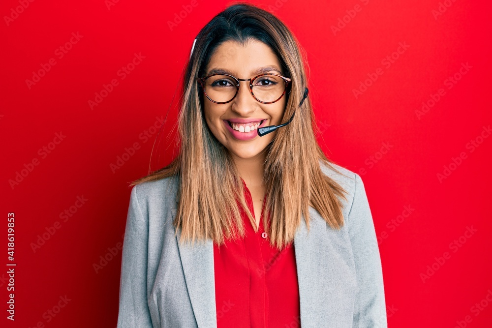 Beautiful brunette woman working at the office wearing operator headset looking positive and happy standing and smiling with a confident smile showing teeth Beautiful brunette woman working at the office wearing operator headset looking positive and happy standing and smiling with a confident smile showing teeth