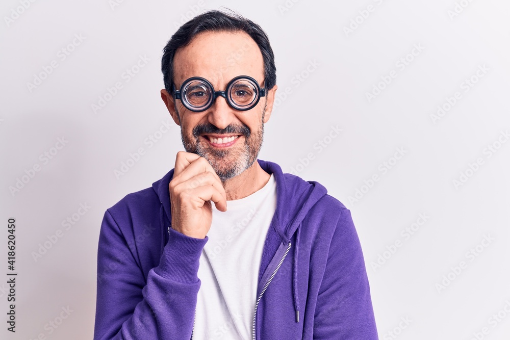 Middle age handsome freaky man wearing dumb glasses over isolated white background smiling looking confident at the camera with crossed arms and hand on chin. Thinking positive. Middle age handsome freaky man wearing dumb glasses over isolated white background smiling looking confident at the camera with crossed arms and hand on chin. Thinking positive.