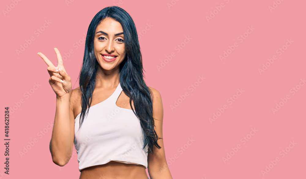 Beautiful hispanic woman wearing casual clothes smiling looking to the camera showing fingers doing victory sign. number two. Beautiful hispanic woman wearing casual clothes smiling looking to the camera showing fingers doing victory sign. number two.