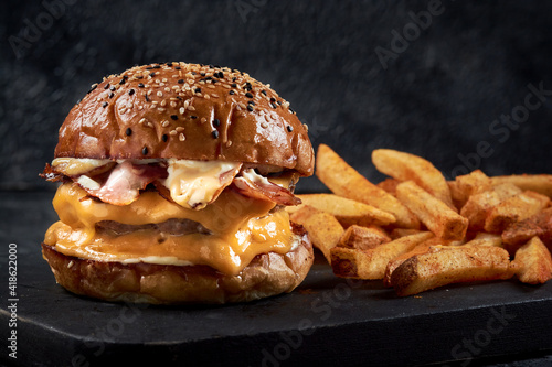 Obraz na płótnie hamburguesa doble carne con tocineta queso y cebolla frita en un fondo negro  y