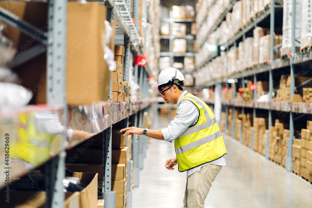 Portrait of smiling asian engineer man order details checking goods and supplies on shelves with goods background in warehouse.logistic and business export Portrait of smiling asian engineer man order details checking goods and supplies on shelves with goods background in warehouse.logistic and business export