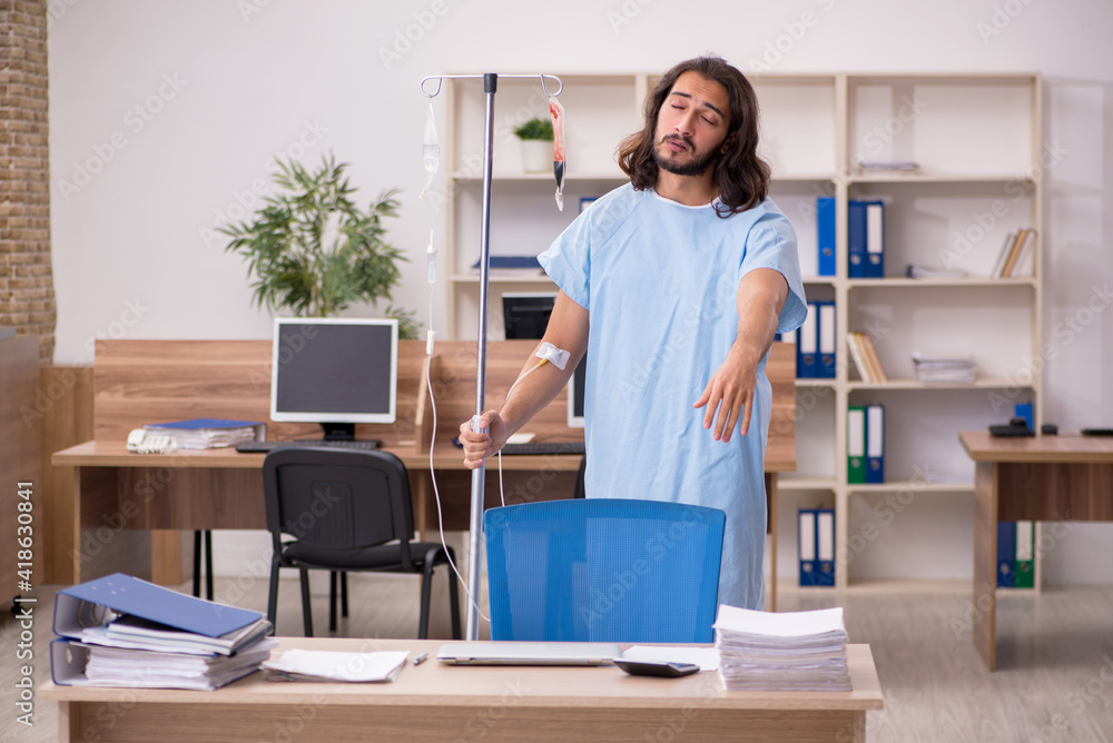 Young sick male employee in blood transfusion concept Young sick male employee in blood transfusion concept