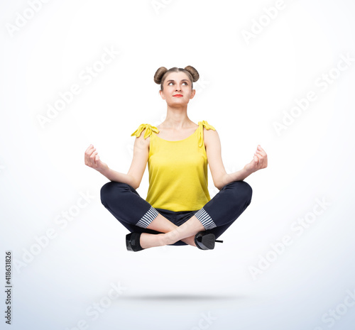 Murais de parede Happy young women in casual clothes meditating levitating in the air on light blue background