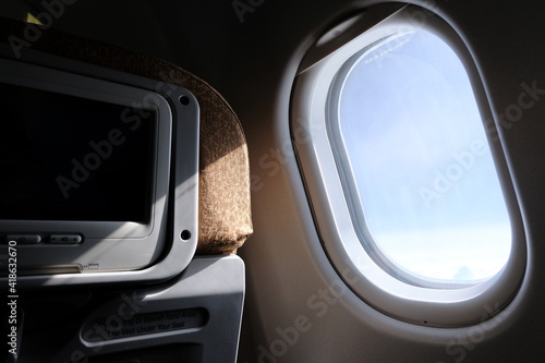 Airplane window with inflight entertainment shining by sun photo