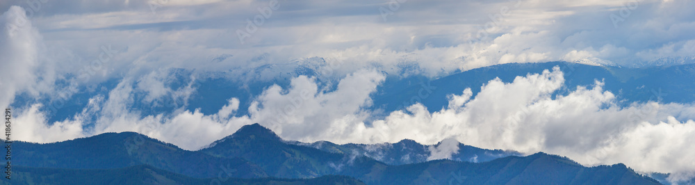 Mountains in clouds and fog on a summer morning, panoramic view	
