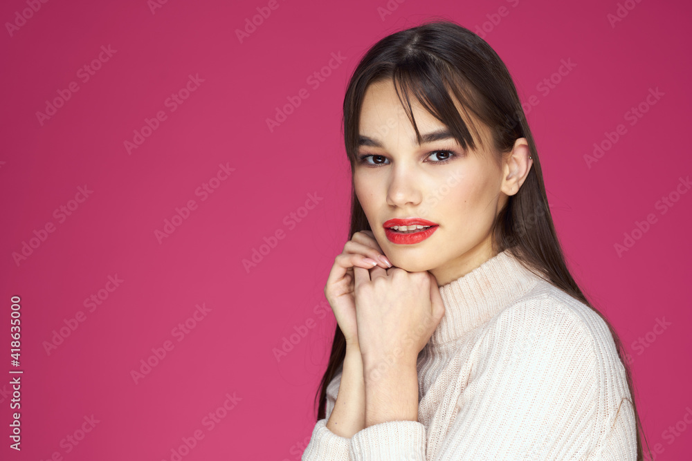 Brunette with long hair red lips cosmetics white sweater pink background cropped view Brunette with long hair red lips cosmetics white sweater pink background cropped view