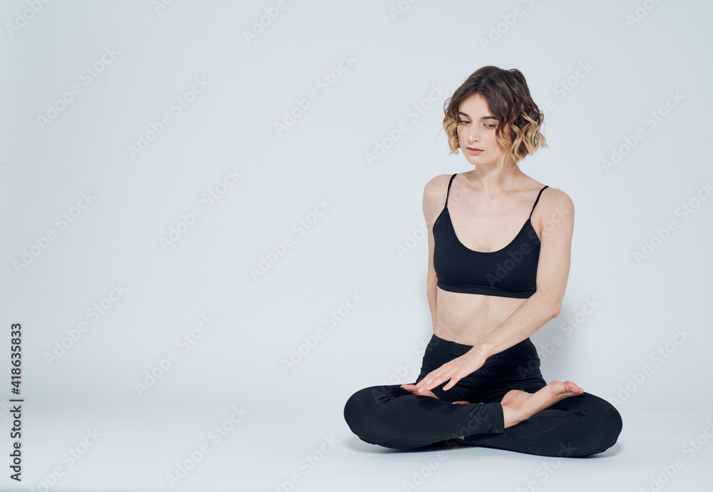 A woman in leggings sits cross-legged on the floor and turns to the sides A woman in leggings sits cross-legged on the floor and turns to the sides